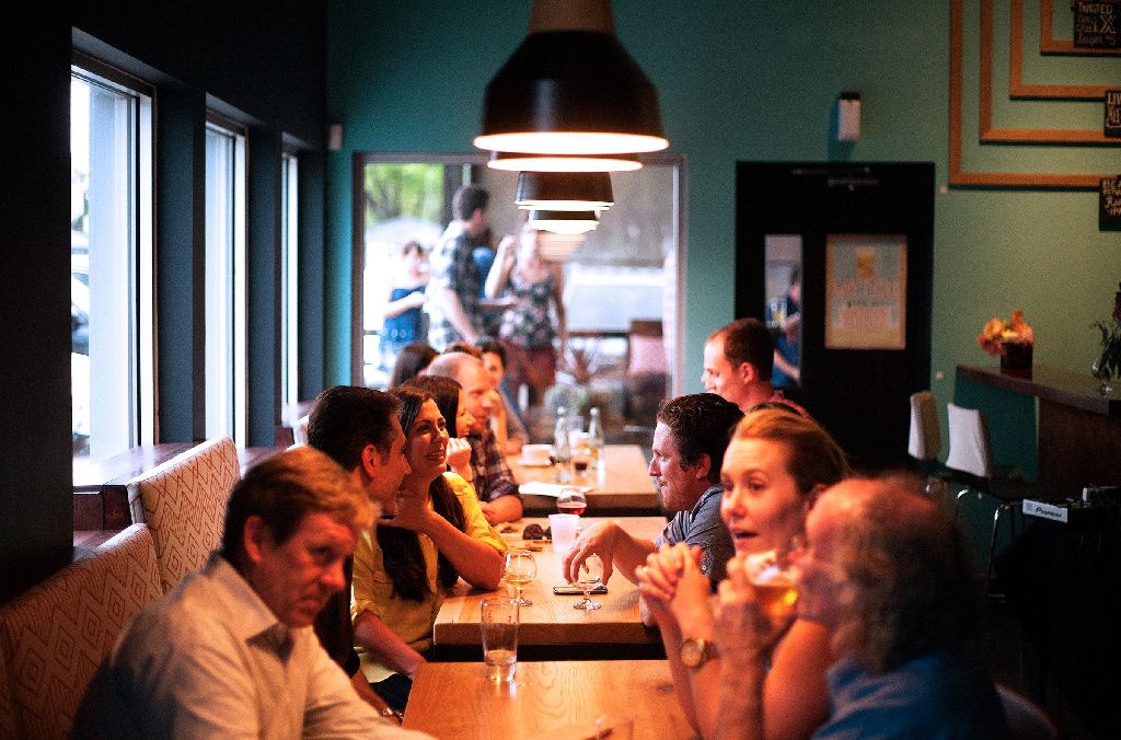 People sitting at tables, talking, at a busy restaurant