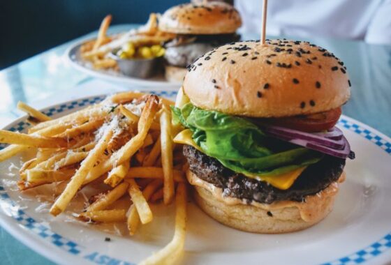 Two plates of cheeseburgers and french fries