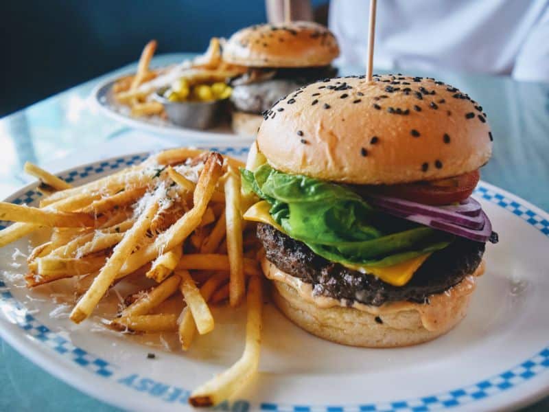 Two plates of cheeseburgers and french fries